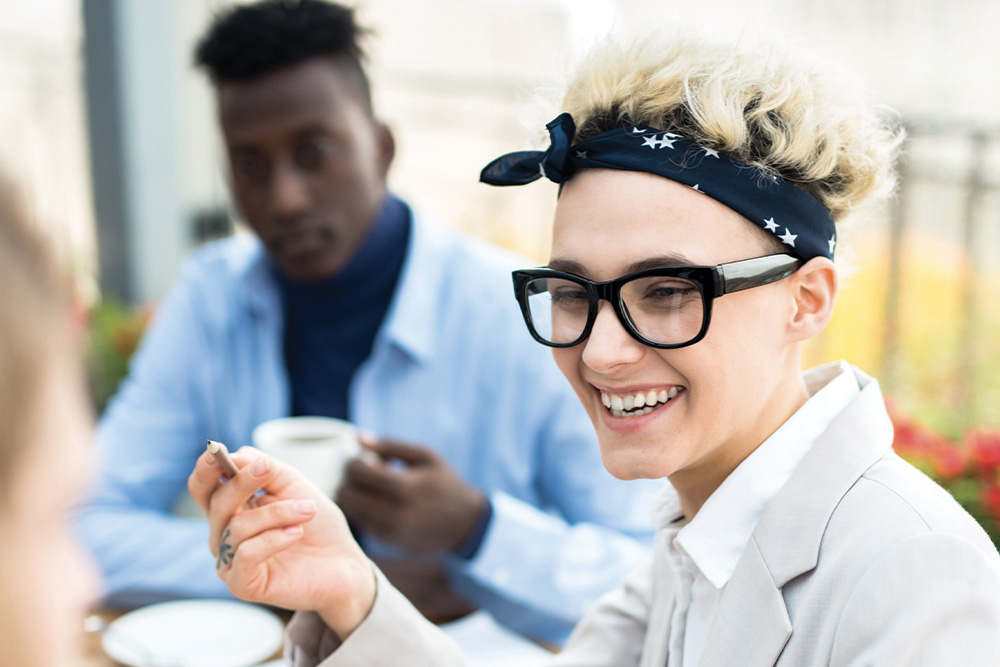 Cheerful young employee laughing during conversation with colleague about plans for new working year