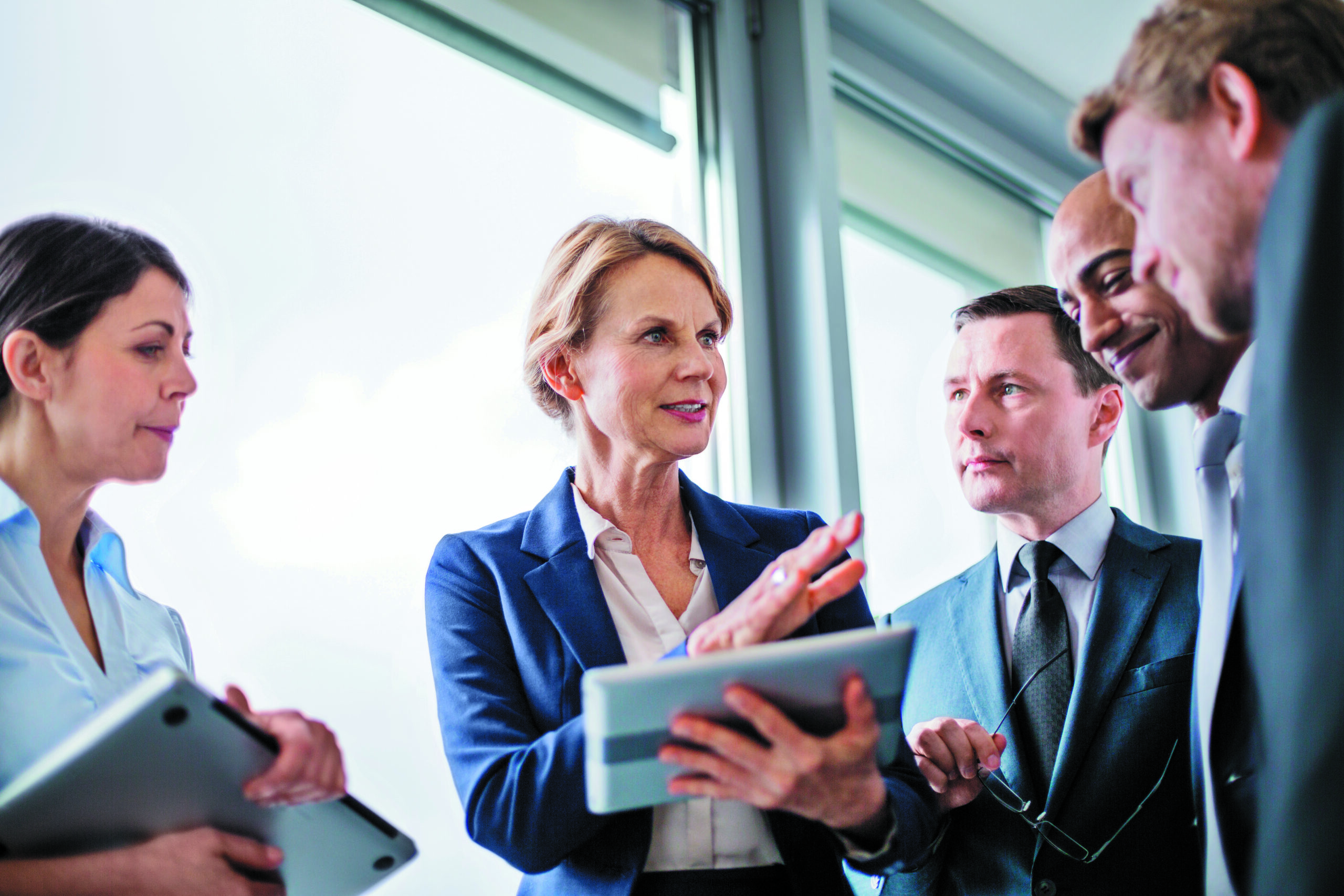 Mature businesswoman explaining new business ideas to colleagues during a standing meeting in office